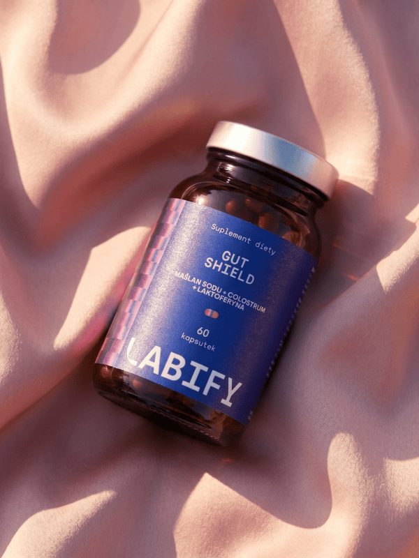LABIFY Gut Shield - zdjęcie 6 LABIFY Gut Shield - butelka leżąca na brzoskwiniowej tkaninie w świetle słonecznym