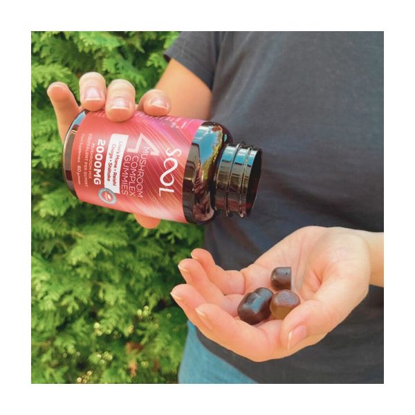 Żelki 4 Mushroom Gummies 60szt - Berry: dłoń trzyma słoik i wysypuje żelki na drugą dłoń, w tle zieleń Żelki 4 Mushroom Gummies 60szt - Berry: dłoń trzyma słoik i wysypuje żelki na drugą dłoń, w tle zieleń